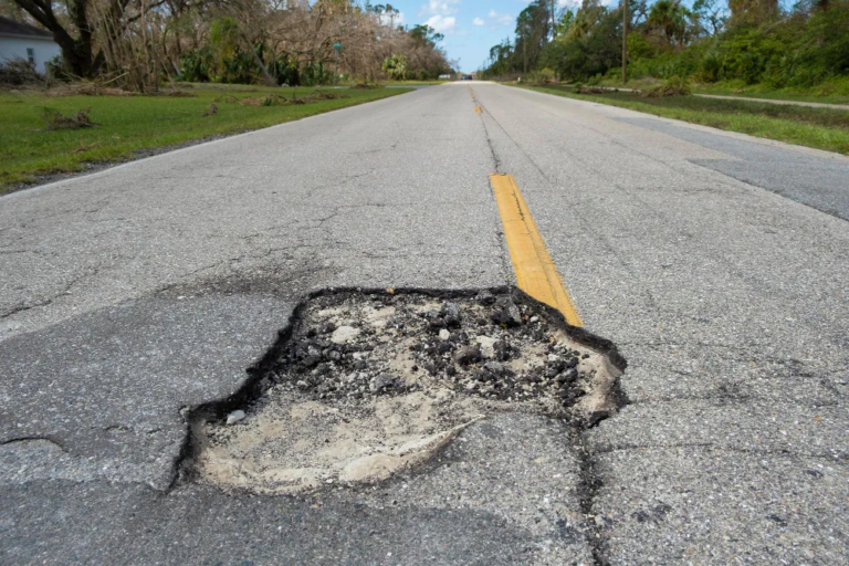 Large pothole on a Scottish road causing a hazard for drivers and cyclists.